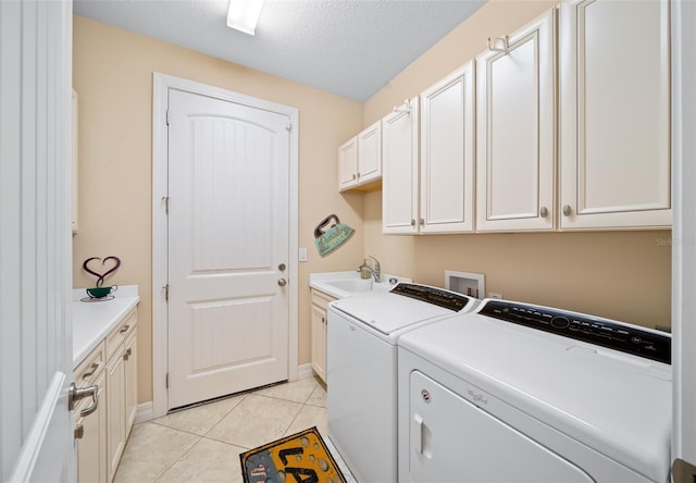 laundry area with cabinets, a textured ceiling, sink, light tile patterned floors, and washing machine and dryer