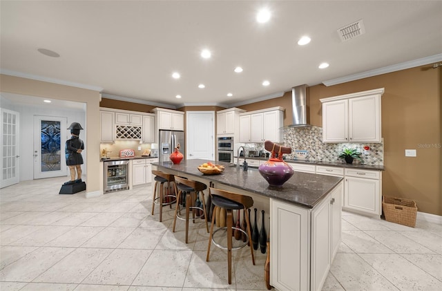 kitchen featuring wall chimney exhaust hood, a large island, white cabinetry, and appliances with stainless steel finishes