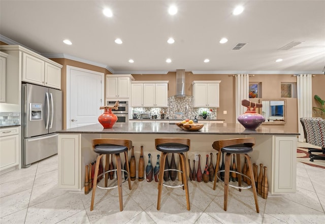 kitchen with a breakfast bar area, a large island, wall chimney range hood, and appliances with stainless steel finishes