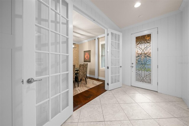 foyer entrance featuring french doors, light tile patterned floors, and crown molding