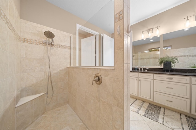 bathroom with a tile shower, tile patterned flooring, and vanity