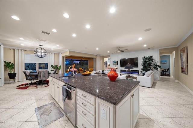 kitchen featuring dishwasher, ceiling fan with notable chandelier, a kitchen island with sink, and sink