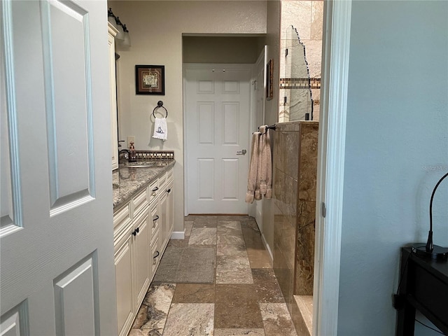 bathroom featuring tiled shower and vanity