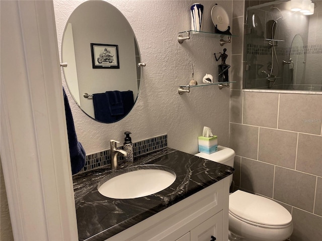 bathroom with tiled shower, vanity, and toilet