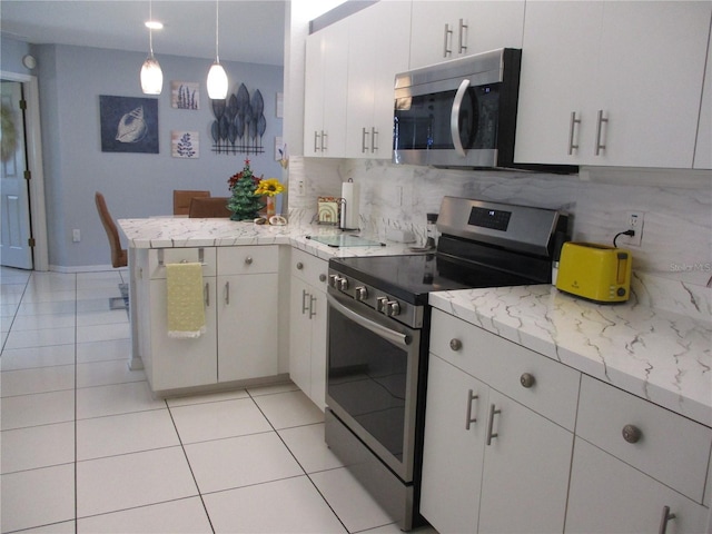 kitchen featuring hanging light fixtures, backsplash, kitchen peninsula, white cabinets, and appliances with stainless steel finishes