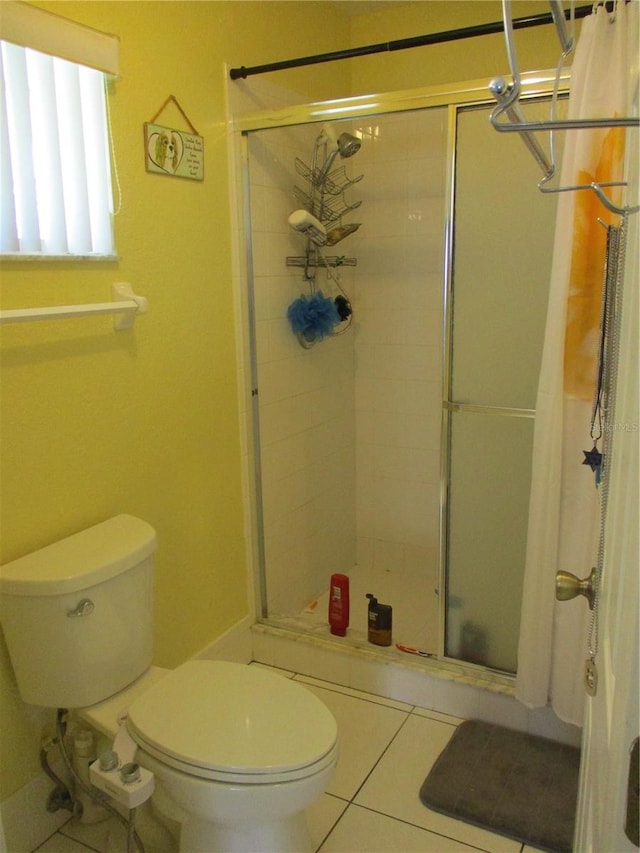 bathroom with tile patterned flooring, toilet, and a shower with door