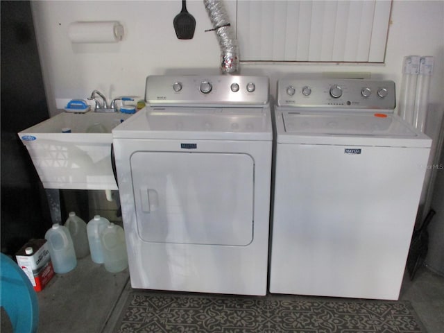 clothes washing area with washing machine and dryer, dark tile patterned floors, and sink