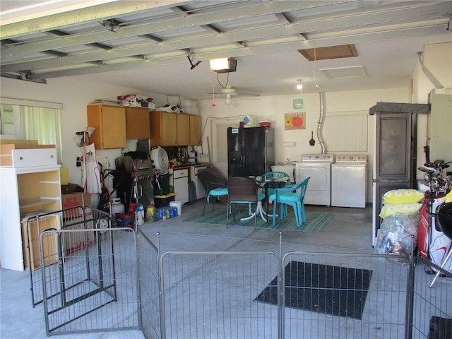 garage featuring black fridge with ice dispenser, a garage door opener, and washing machine and clothes dryer