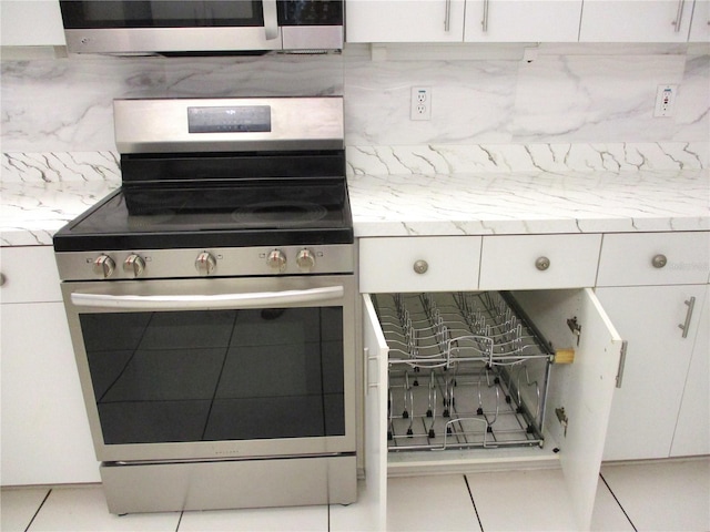 kitchen with stainless steel appliances, white cabinetry, and backsplash