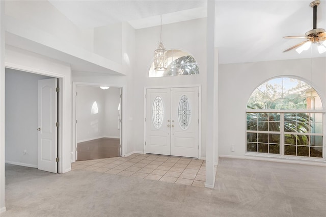 carpeted entrance foyer featuring ceiling fan with notable chandelier and high vaulted ceiling