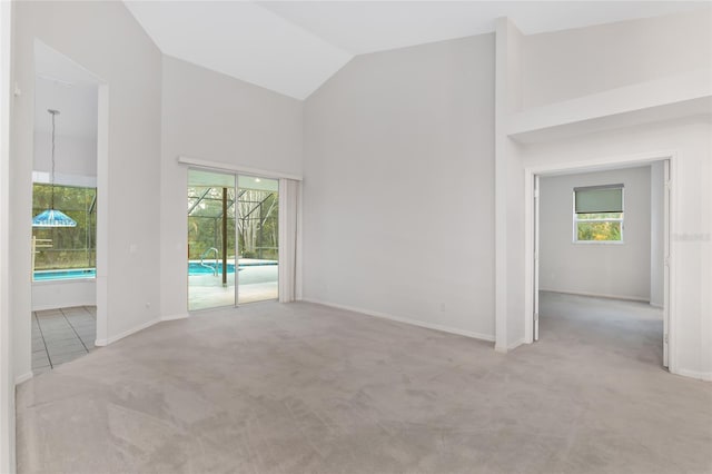 spare room with light carpet and high vaulted ceiling