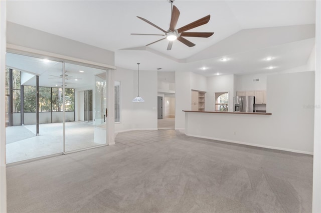 unfurnished living room featuring ceiling fan, light colored carpet, and vaulted ceiling