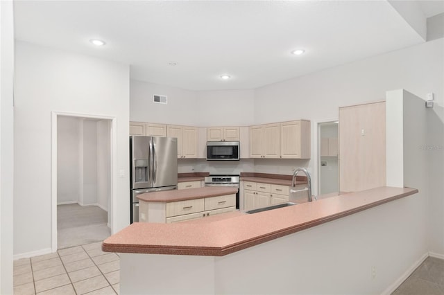 kitchen featuring sink, kitchen peninsula, stainless steel appliances, and cream cabinets