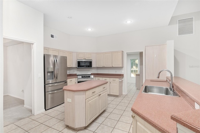 kitchen with sink, a towering ceiling, cream cabinetry, light tile patterned floors, and appliances with stainless steel finishes