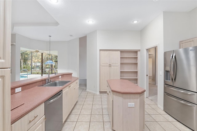 kitchen with sink, stainless steel appliances, light tile patterned floors, decorative light fixtures, and a kitchen island