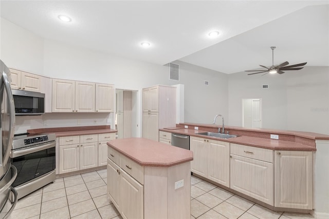 kitchen with sink, ceiling fan, light tile patterned floors, appliances with stainless steel finishes, and a kitchen island