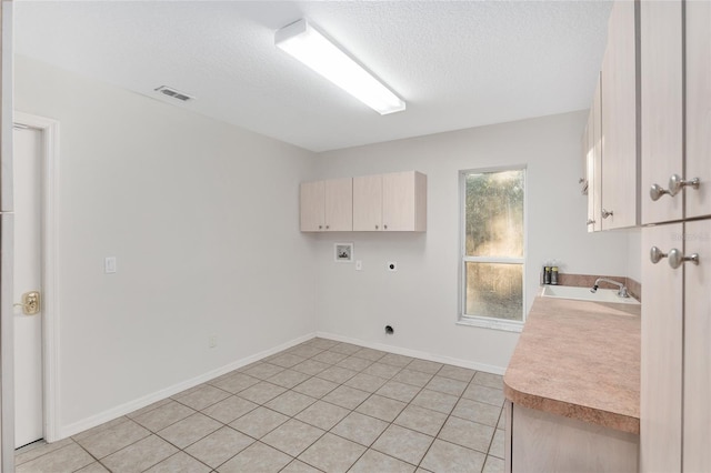 clothes washing area featuring cabinets, sink, washer hookup, light tile patterned floors, and hookup for an electric dryer