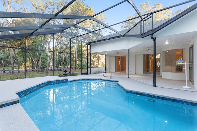 view of swimming pool with glass enclosure, ceiling fan, and a patio