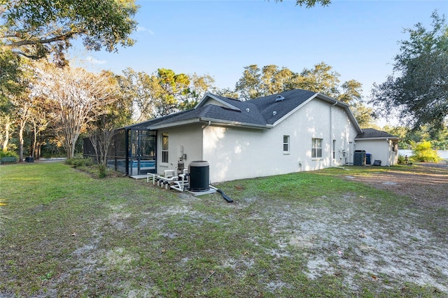 rear view of house with a yard, glass enclosure, and cooling unit