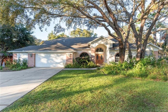2843 W Elm Blossom St, Beverly Hills, FL 34465 - view of front facade featuring an attached garage, a front lawn, driveway, and stucco siding