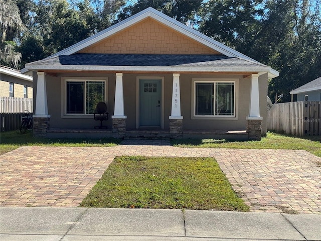 bungalow-style house featuring covered porch and a front lawn