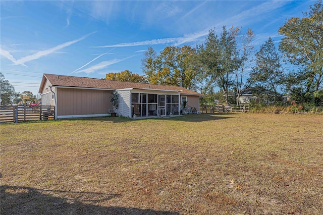 rear view of house featuring a lawn and a sunroom