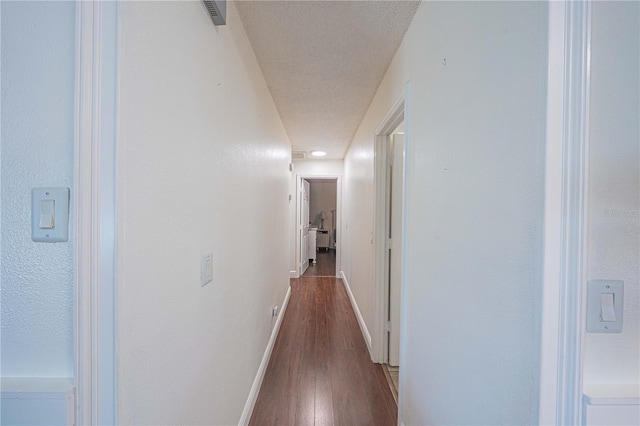 hall featuring a textured ceiling and dark hardwood / wood-style floors