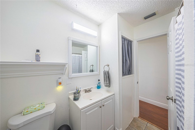 bathroom with hardwood / wood-style floors, vanity, a textured ceiling, and toilet