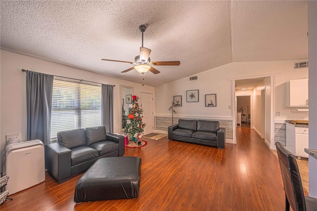 living room with a textured ceiling, hardwood / wood-style flooring, vaulted ceiling, and ceiling fan