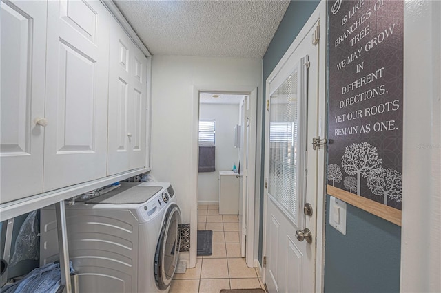 laundry room with washing machine and clothes dryer, light tile patterned floors, and a textured ceiling