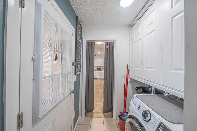 clothes washing area with washer / clothes dryer, light tile patterned floors, cabinets, and a textured ceiling