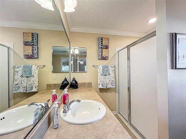 bathroom with vanity, a shower with shower door, a textured ceiling, and ornamental molding