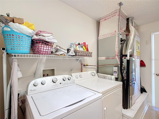 laundry room featuring washing machine and dryer, light tile patterned floors, a textured ceiling, and heating unit