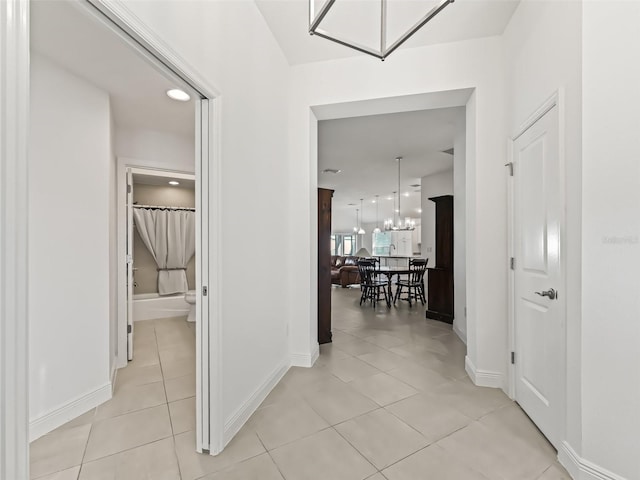 corridor featuring light tile patterned floors and an inviting chandelier