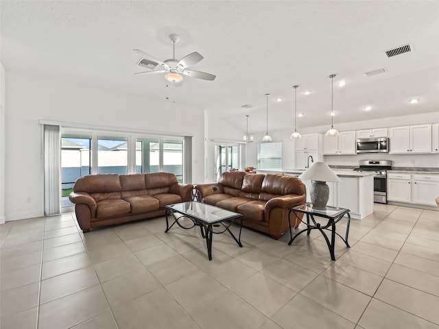 tiled living room featuring ceiling fan, lofted ceiling, and sink