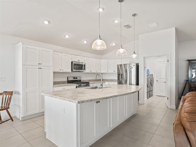 kitchen with sink, pendant lighting, vaulted ceiling, washer and dryer, and appliances with stainless steel finishes