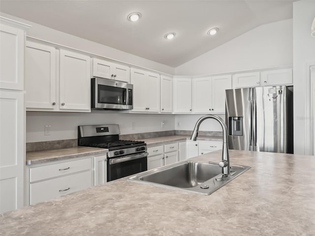 kitchen featuring white cabinets, sink, appliances with stainless steel finishes, and vaulted ceiling