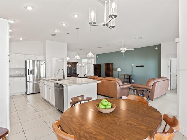 tiled dining space featuring ceiling fan, sink, and lofted ceiling