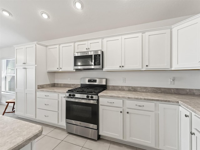 kitchen with white cabinets, stainless steel appliances, and light tile patterned flooring