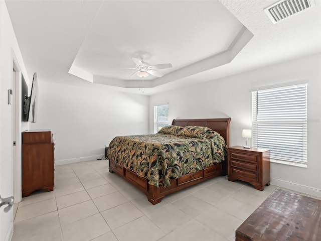 bedroom featuring a raised ceiling, ceiling fan, and light tile patterned flooring