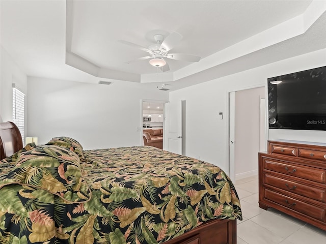 tiled bedroom with a tray ceiling and ceiling fan