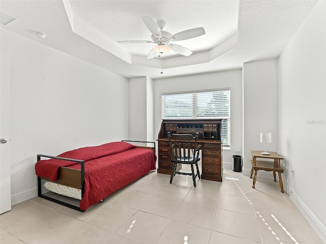 bedroom featuring ceiling fan, a textured ceiling, and a tray ceiling