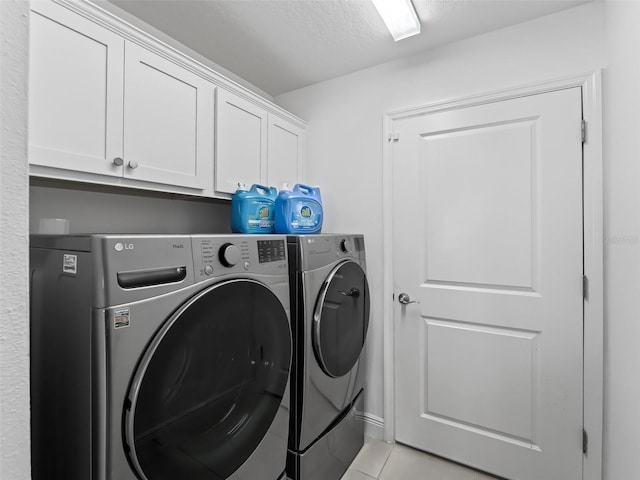 laundry room featuring washer and dryer, light tile patterned floors, a textured ceiling, and cabinets