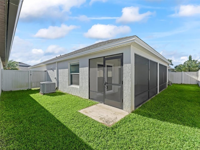 rear view of property featuring a yard, central air condition unit, and a sunroom