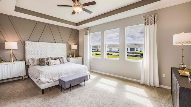 carpeted bedroom featuring a tray ceiling and ceiling fan