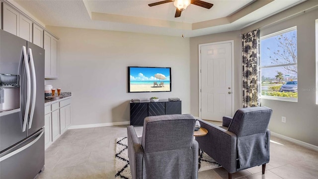 living area featuring a tray ceiling, light tile patterned flooring, and a healthy amount of sunlight