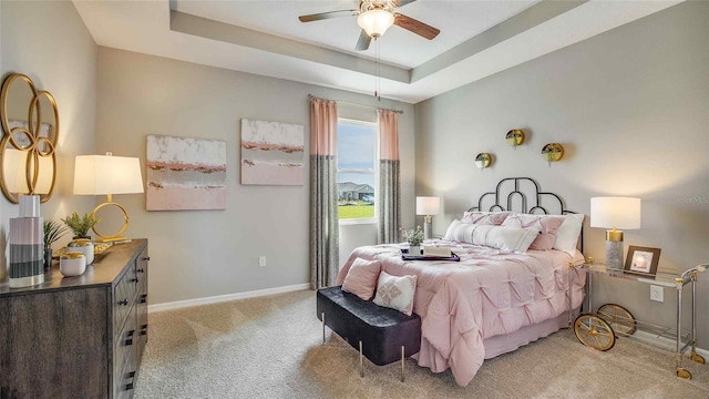 carpeted bedroom featuring ceiling fan and a tray ceiling