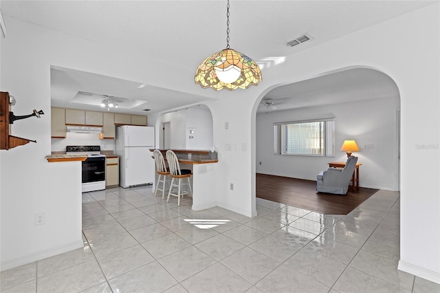 kitchen with light wood-type flooring, a textured ceiling, white appliances, and ceiling fan