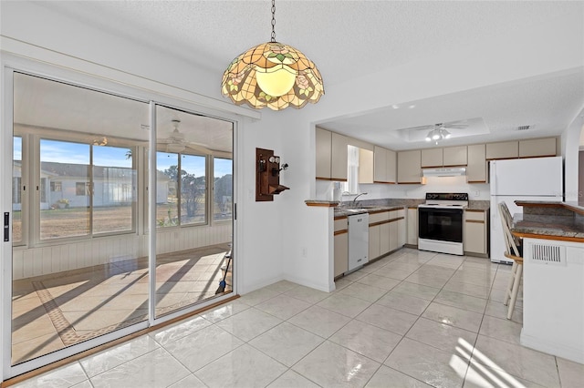 kitchen featuring a textured ceiling, white appliances, sink, decorative light fixtures, and light tile patterned flooring