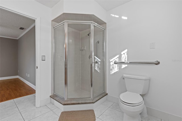 bathroom featuring tile patterned flooring, a textured ceiling, toilet, and a shower with door